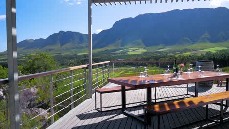 scenic wine tasting table on deck overlooking valley with vineyards and mountain in distance