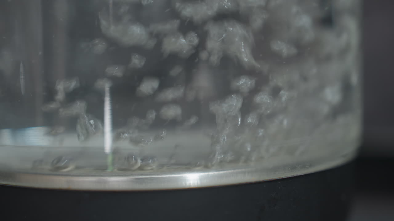 Water Boiling Closeup, Detailed View Of Steaming Kettle Water, Closeup Of Boiling Water Inside Reflective Kettle, Microbubbles Ascend In Glass Kettle Under Subdued Studio Lighting Conditions