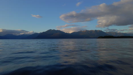 flying above water surface on lake te anau with mountains in the background