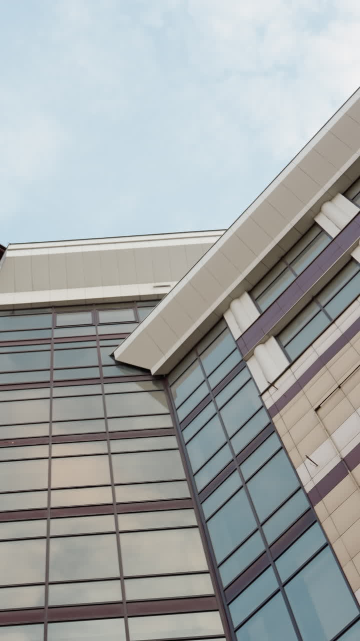 vista cercana de un edificio de la ciudad moderna con una fachada de vidrio elegante y diseño arquitectónico, la perspectiva lateral de la estructura del edificio contra un telón de fondo de un cielo azul claro
