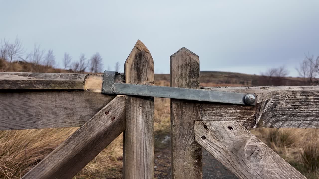 Accesso rurale e confine. Vista ravvicinata di un cancello in legno con chiavistello in metallo in un campo. Accesso al terreno, diritti di proprietà, vita di campagna, ingresso di fattoria, fascino rustico e paesaggio privato.