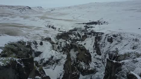 icelandic landscape covered with snow and ice in a rocky formation gorje, aerial drone shot, iceland