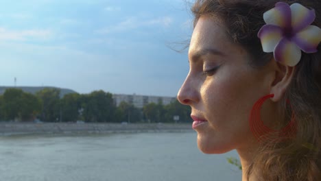 cerrar el perfil de una joven que abre los ojos después de la meditación junto al río en una tarde soleada