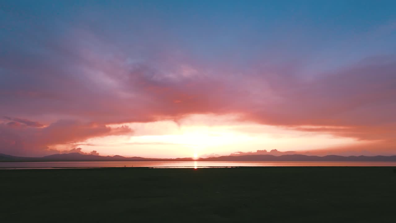 Prise de vue FPV en travelling avant vers le coucher de soleil sur le Song Kul, steppe alpine sans fin et lumière déclinante s’étendant jusqu’au crépuscule