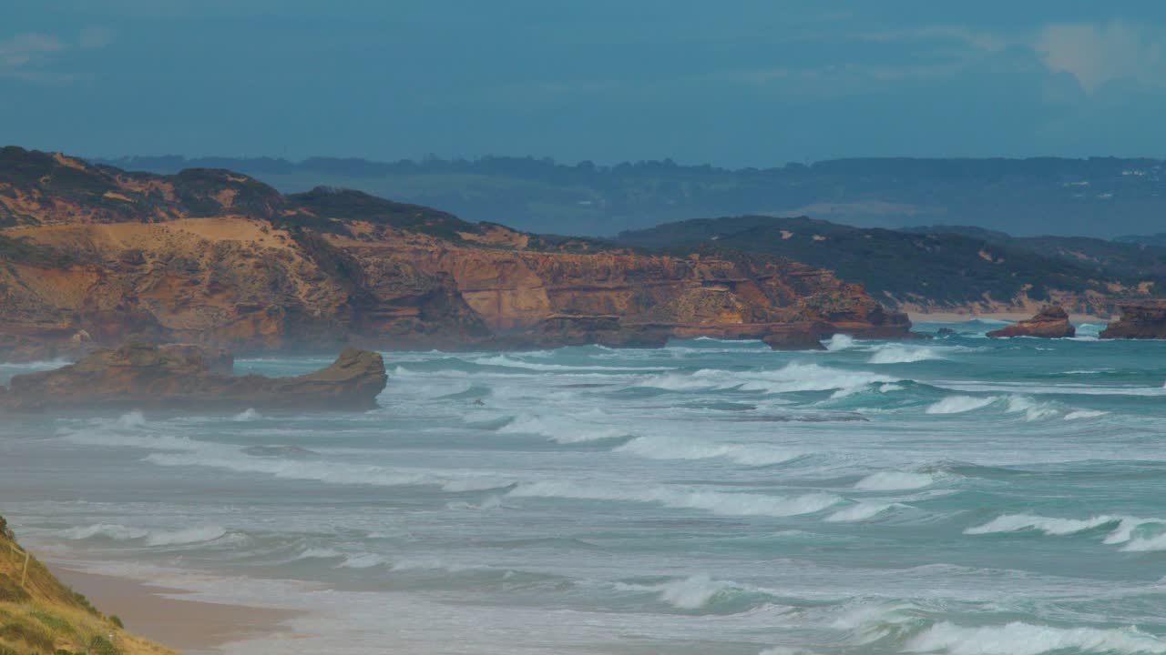 Dynamic ocean waves hit limestone cliffs under daylight, wide shot, steady camera, natural atmosphere