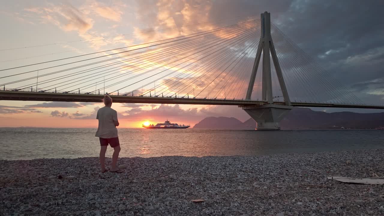 Woman on peaceful beach watches amazing sunset Bay of Corinth horizon