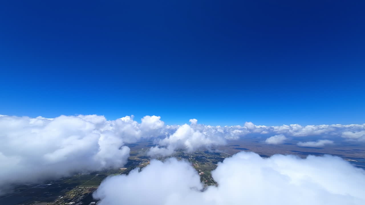 Lovely fluffy clouds hanging in the sky. FPV drone turns in the cloudscape revealing the view on the city view below.
