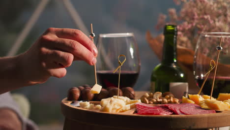 a close-up shot of a man enjoying a delicious cheese plate with red wine, a perfect spread for a romantic dinner