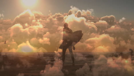 animatie van blauwe hemel en wolken over blanke man die met een surfplank op het strand loopt