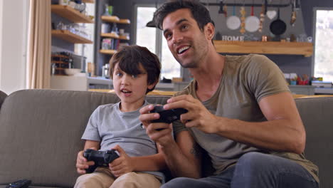 father and son sitting on sofa in lounge playing video game