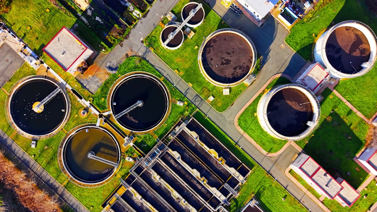 Straight down bird's eye view of round clarifiers and rectangular aeration pools at a purification site. Overhead view of sewage treatment facility tanks.