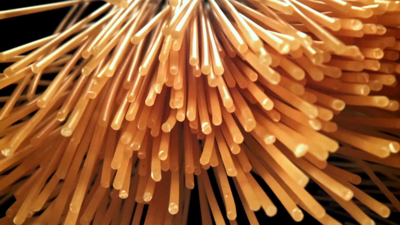 Nærbillede af ukogt spaghetti-pasta, der stiger op mod en sort baggrund