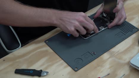 Man unscrewing and taking screen off Apple iPhone to repair and replace