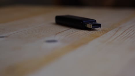 black usb stick lies on a wooden board and rotates against a dark background