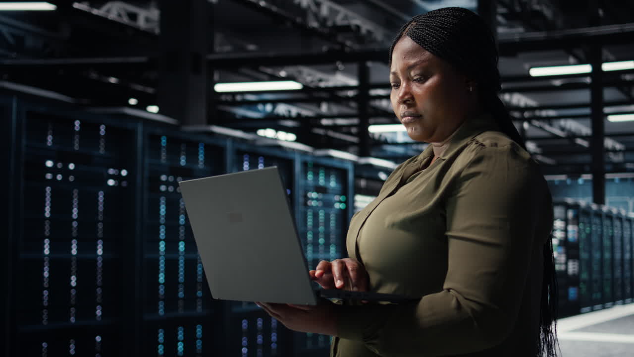 Software developer in data center using laptop to upgrade systems