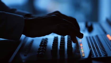 sound engineer working on a mixing console in a dimly lit studio