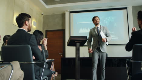 caucasian male business speaker finishing his conference in a meeting and going away cheerfully while people clapping