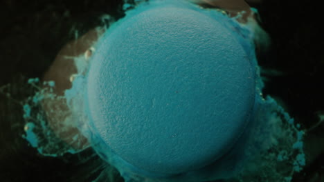 close-up of a blue round object with a textured surface, possibly a macaron or painted object, after an explosion of liquid or paint