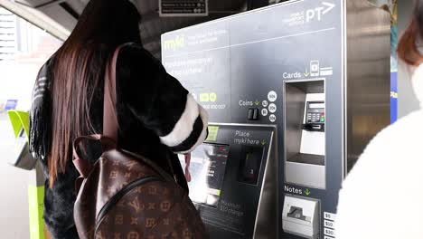 person using a ticket machine at a station