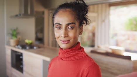 video of happy biracial woman looking at camera at home