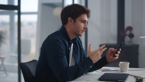 Business-man-having-conference-on-smartphone.-Man-waving-hands-after-video-call.