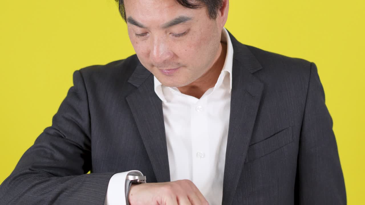Man in formal suit checks wristwatch, waits, and reacts with skeptical expression, studio lighting