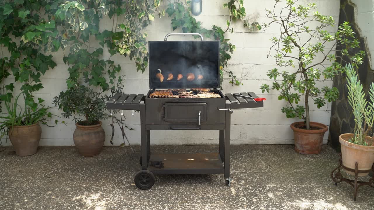 Cooking a delicious pork ribs with sweet potatoes on BBQ grill in backyard house