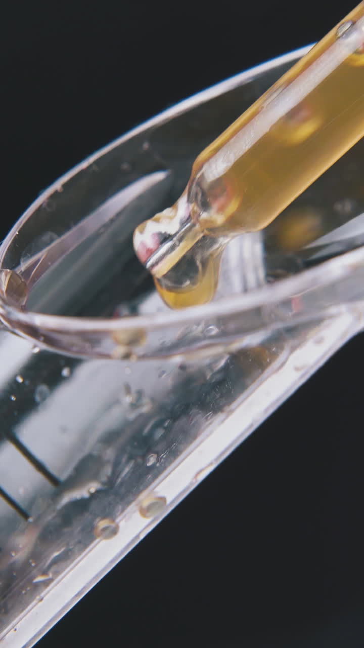 man hand takes brown liquid from measuring spoon with pipette on dark background extreme close view