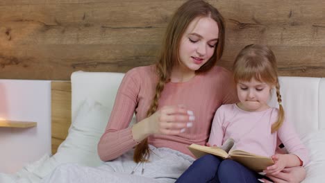 Junge-Mutter-Liest-Kind-Tochter-Kind-Mädchen-Im-Nachtschlafzimmer-Gute-Nacht-Geschichtenbuch-Märchen-Vor