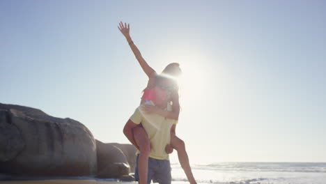 Attractive-man-giving-girlfriend-piggyback-couple-enjoying-nature--on-the-beach