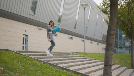 woman walking upstairs with yoga mat