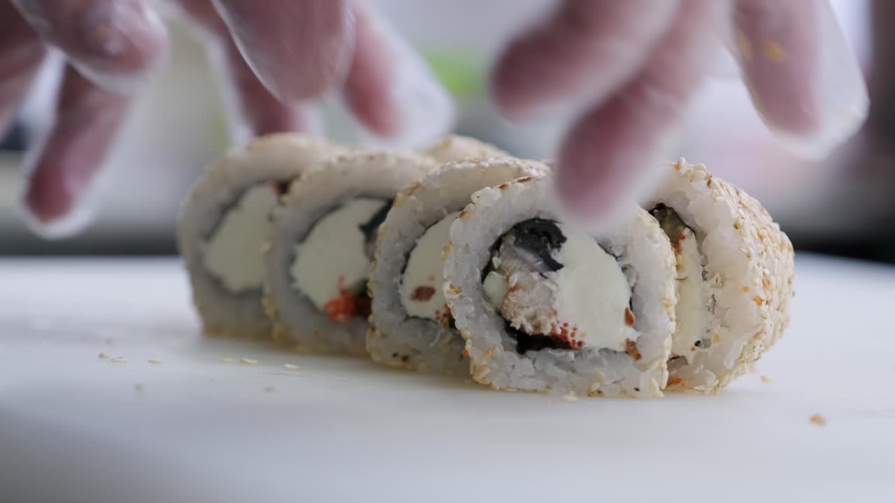 cocinar las manos girar rollos preparados de pescado y arroz en una tabla blanca
