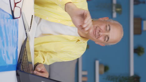 vertical video of home office worker old man waving at camera.