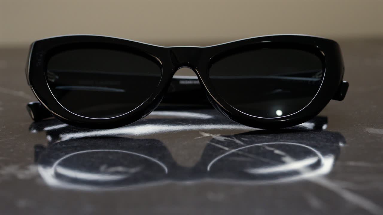 Close up of a black pair of sunglasses on a black surface