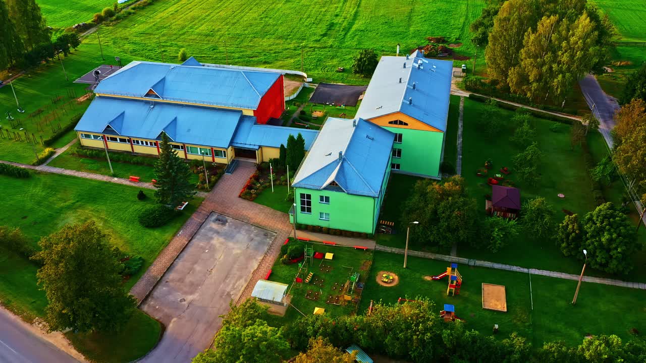 Aerial view of school building and playground in green countryside setting