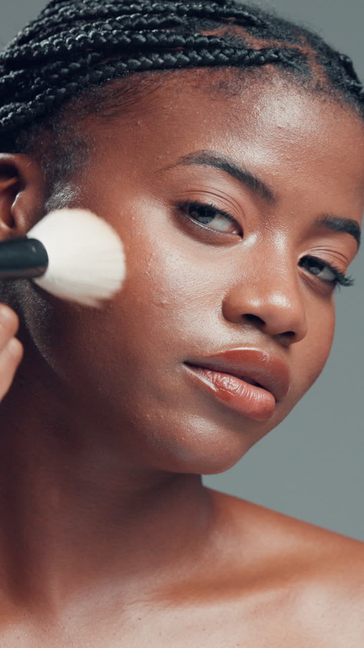 Nærbillede af ung, sort kvinde, der lægger makeup med en pensel