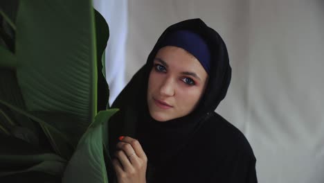hermosa mujer musulmana en tradicional vestido de abaya árabe con planta verde