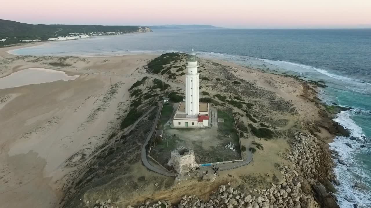 drone revelando el faro y las partes circundantes de la playa a orillas de cádiz en españa