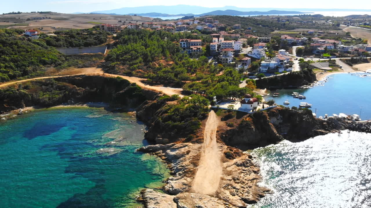 Aerial drone view of the Nea Roda situated on the Aegean sea coast, Greece. Multiple buildings with greenery, church near the shore