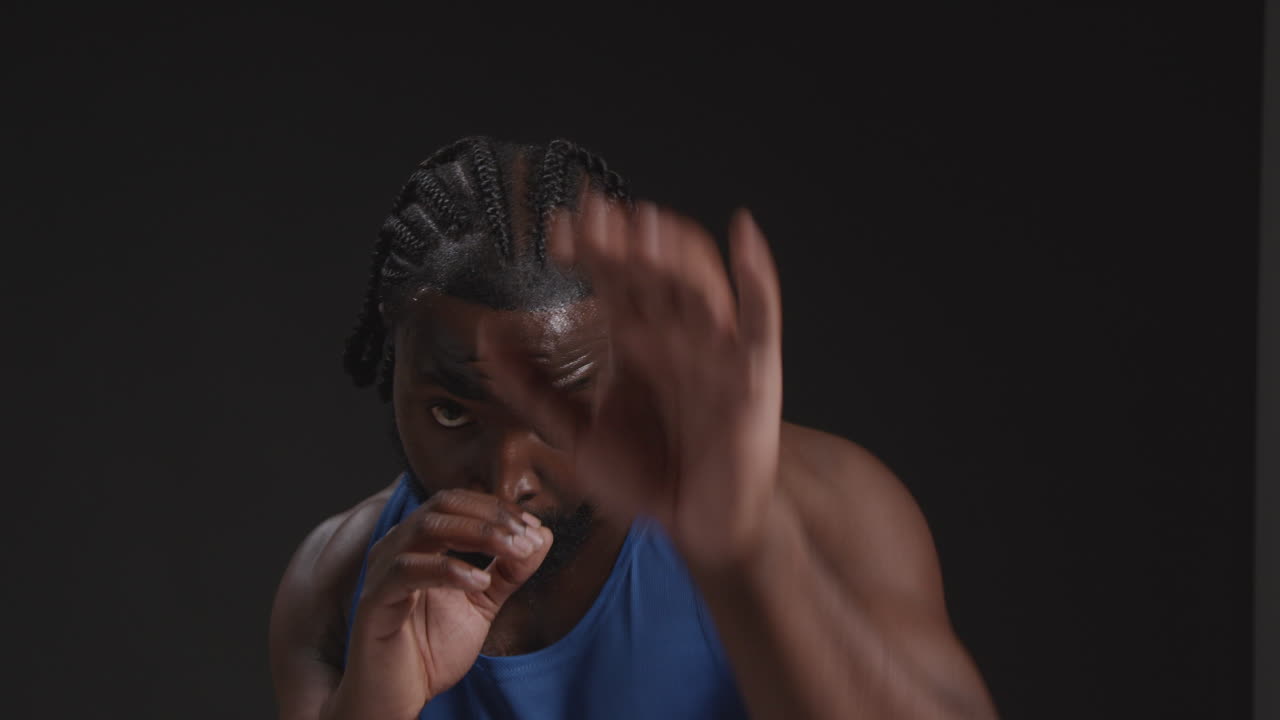 retrato de estudio en primer plano de un boxeador masculino entrenando en el gimnasio luchando hacia la cámara y calentándose preparándose para la pelea contra un fondo negro
