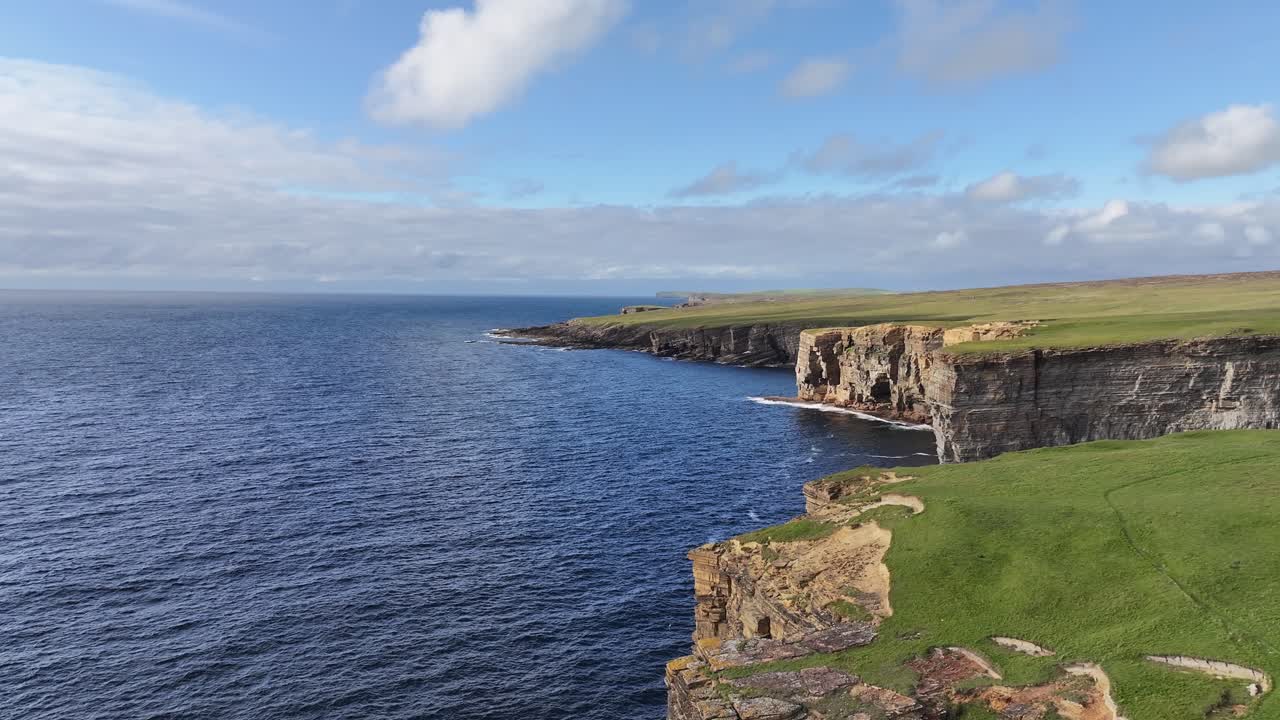volando sobre la costa de orkney, escocia, reino unido, vista aérea de acantilados, paisaje verde y horizonte marino
