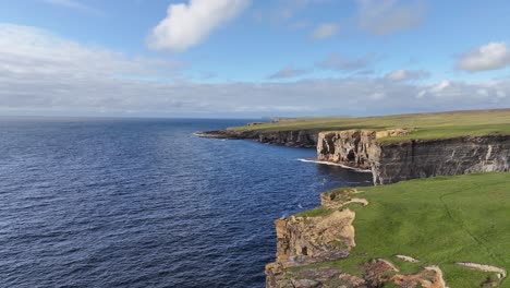 flying above coastline of orkney, scotland uk, aerial view of cliffs, green landscape and sea horizon