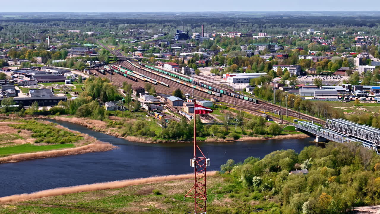 Sorting site near industrial warehouse with silos, wide angle aerial from town edge