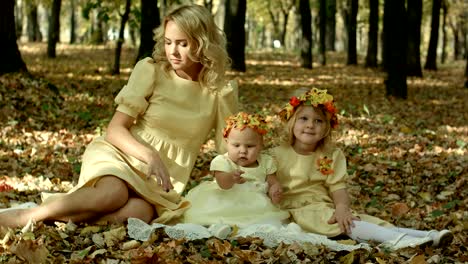 young mother with maple leaves sitting with children