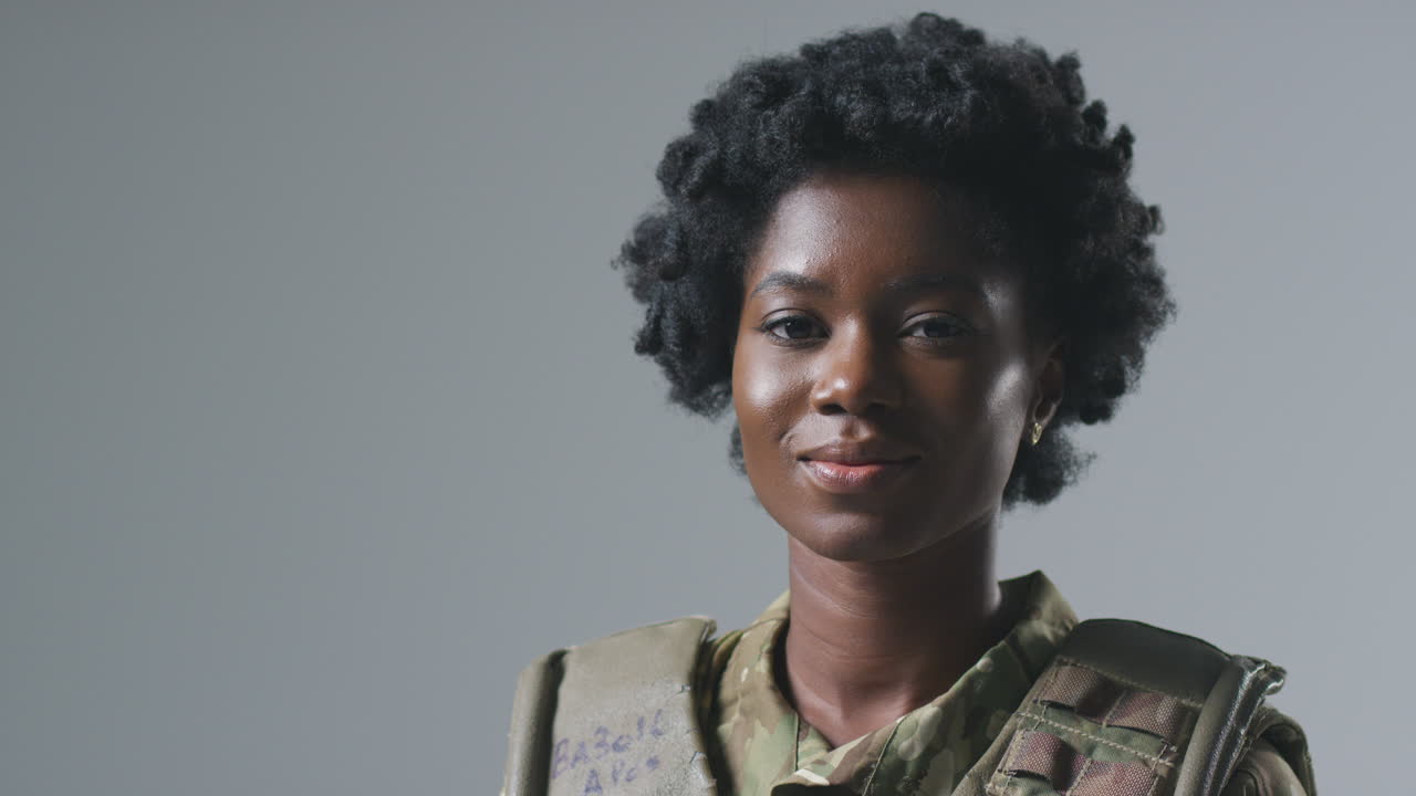 студийный портрет серьезной молодой женщины-солдата в военной форме на простом фоне