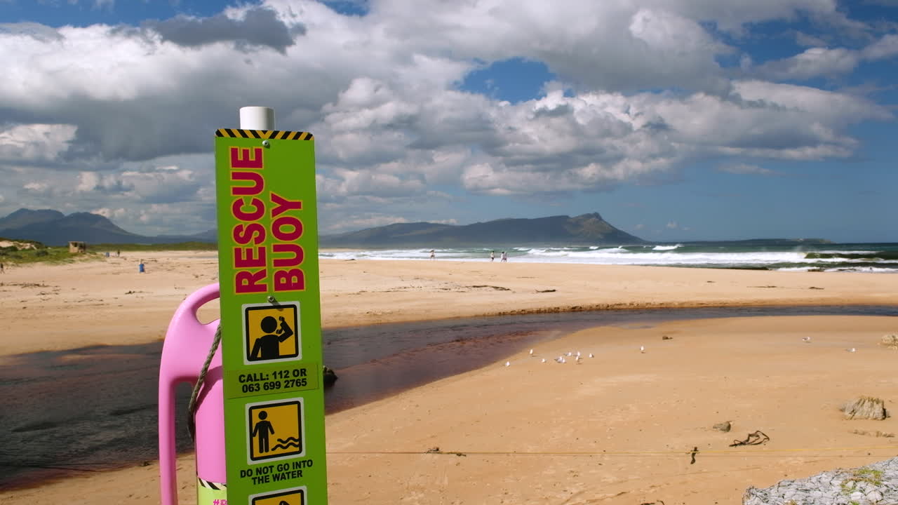 Kleinmond's blue flag beach on summer's day, pink lifebuoy on pole for emergency