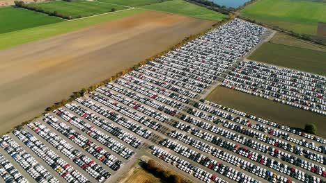 aerial footage of finished cars ready to be shipped on huge distribution center