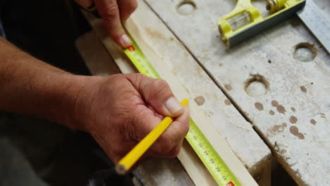 focus on carpenter hands measuring wood