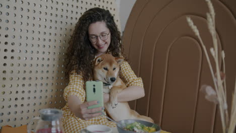woman taking selfie with her dog in a cafe