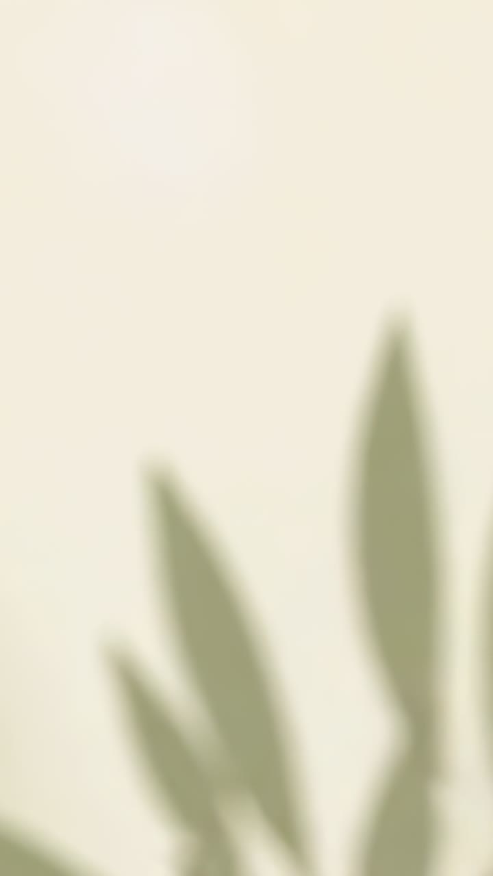Vertical video: Revealing frames green leaf motif moving from right across beige wall, copy space